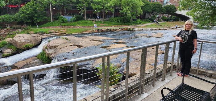 Pausing at a railed overlook to take in the cascading Reedy River at Falls Park in downtown Greenville.