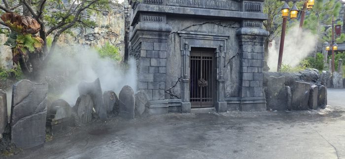 The fog-shrouded Catacombs entrance glows under lantern light as evening falls.