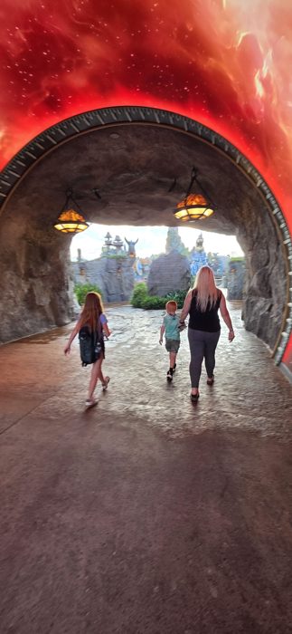Walking through a glowing red tunnel with the kids, the family heads toward the worlds beyond the entrance.