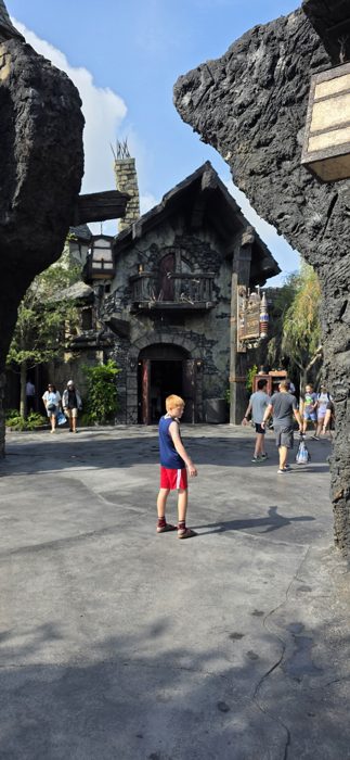 One of the kids pauses in the plaza in front of a crooked stone cottage.
