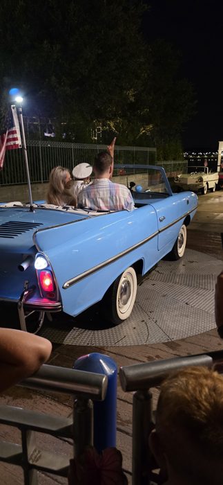 The Amphicar idles at the dock with headlights glowing, ready to roll right into the water.