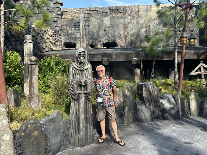 Posing next to a hooded, scythe-wielding statue outside the crypt-like ruins.