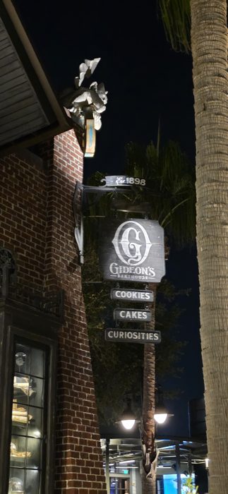 The moody Gideon's Bakehouse sign glows above the walkway, promising cookies, cakes, and curiosities.