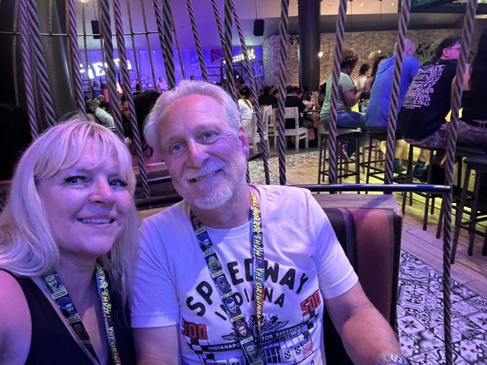 A selfie for the two of us at a lively restaurant booth, string lights and rope decor overhead.