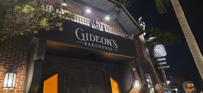 The crowd gathers outside Gideon's dramatic dark storefront under the palms.