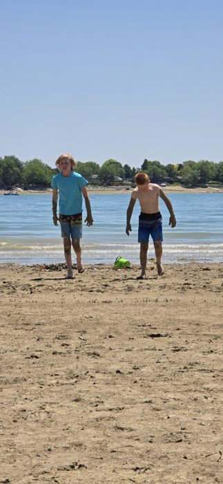 The boys catching their breath on the beach with the lake stretching out behind them.