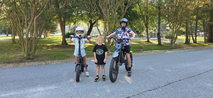 The whole crew lines up with their e-bikes under the shady trees before heading out.