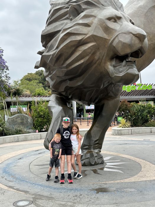 The kids climb the famous bronze lion sculptures at the San Diego Zoo entrance plaza.