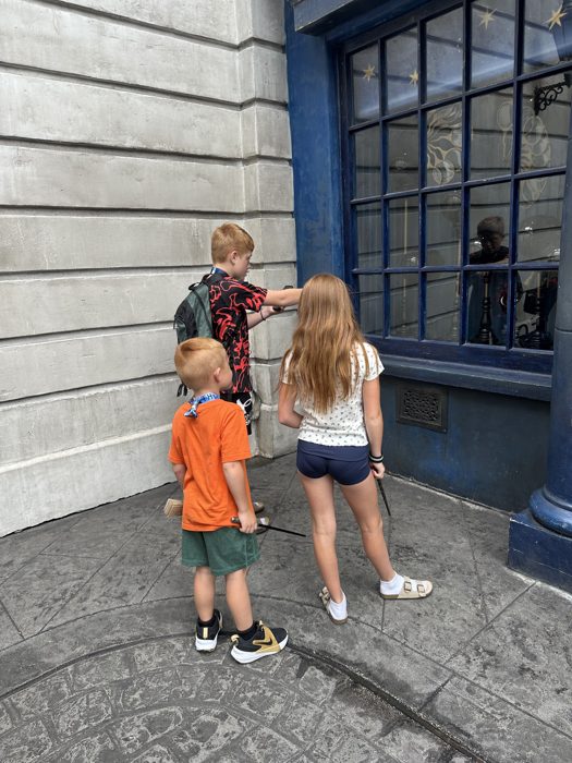 The kids crowd in close, wands out, trying to work the window display.