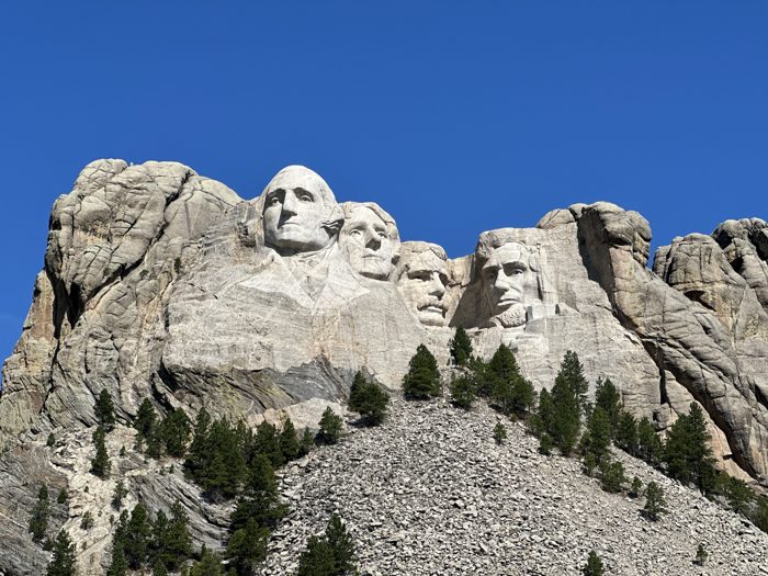 A crisp telephoto look at the carved faces against a deep blue sky.
