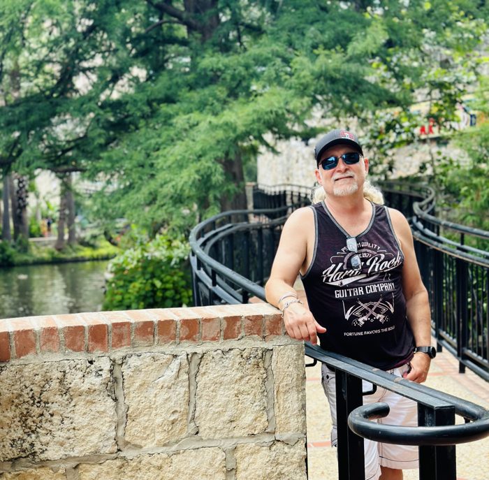 Dad striking a pose by the railing above the leafy River Walk.