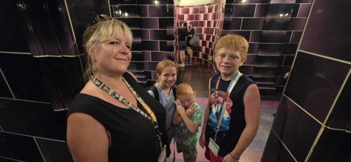 The family gathers in Diagon Alley's ornate tiled corridor, waiting for the ride to start.