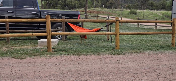 The red hammock strung up and waiting between the fence rails at our shady spot.