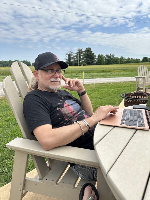 Working remotely from a camp chair with the laptop balanced and coffee close at hand.