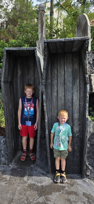 The boys strike a pose standing inside a pair of oversized stone coffins.