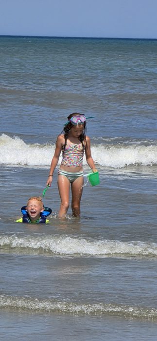 The splashing game carries on as waves roll in around the kids at the beach.
